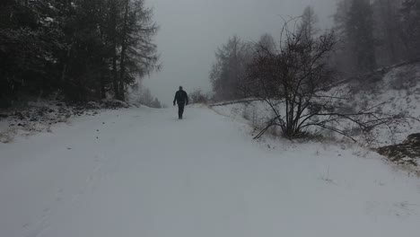 Drone-shot-following-a-man-walking-in-the-snow.